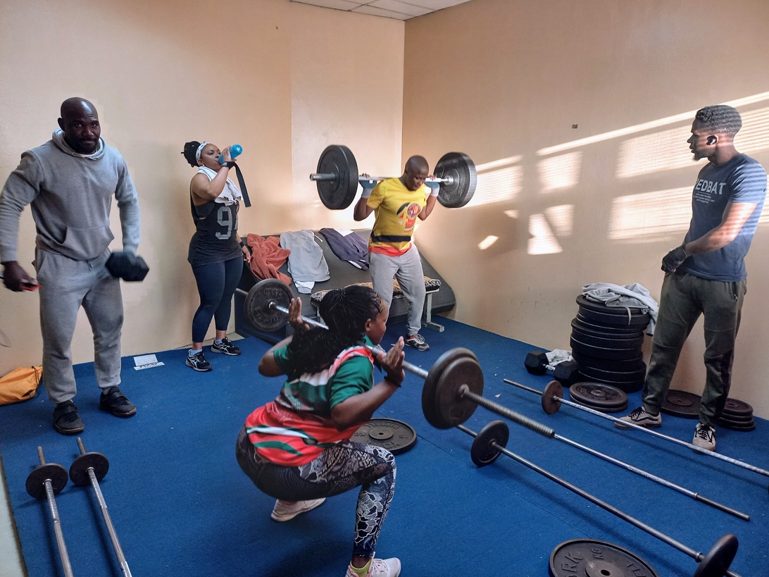 En grupp människor som styrketränar i ett gym, vilket visar på direkt kommunikation mellan tränare och aktiva.